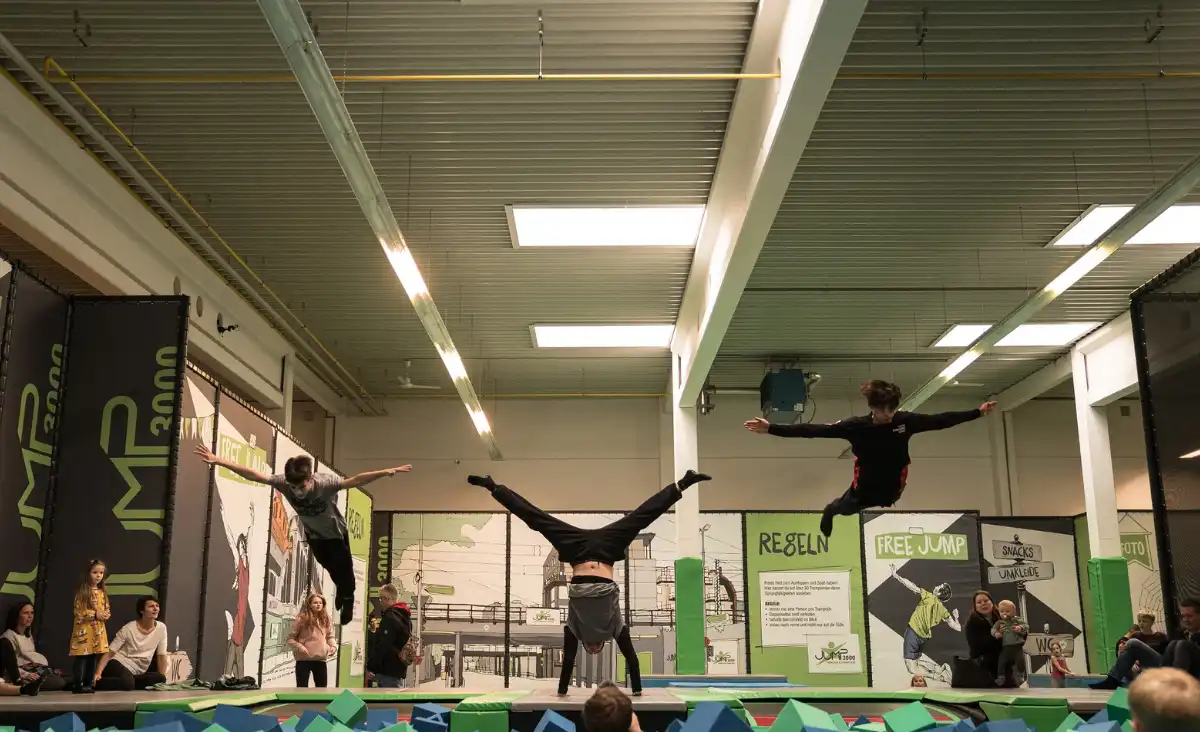 Eine Gruppe von Menschen führt einen Trick auf einem Trampolin aus und zeigt beeindruckende akrobatische Fähigkeiten.