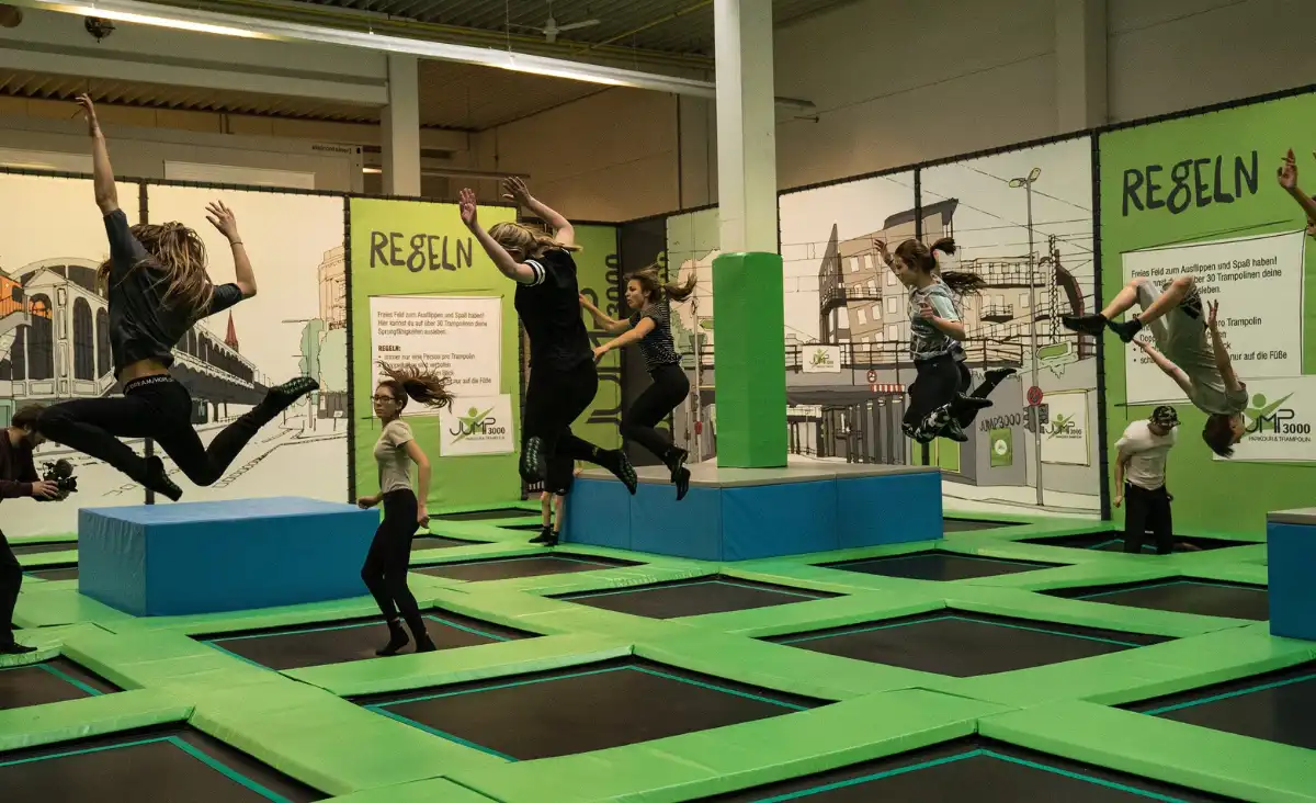 Eine Gruppe von Menschen springt fröhlich auf Trampolinen in einem Indoor-Trampolinpark.