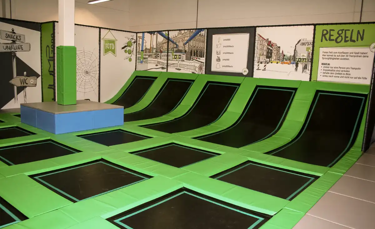 Ein Trampolinpark mit grünen und schwarzen Trampolinen, ideal für Spaß und Bewegung in einer lebhaften Umgebung.