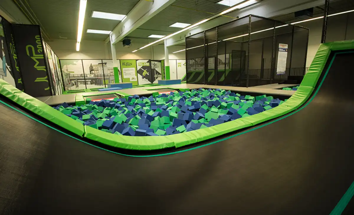 Ein großer Indoor-Trampolinpark mit bunten Bällen in verschiedenen Farben, die überall verteilt sind.