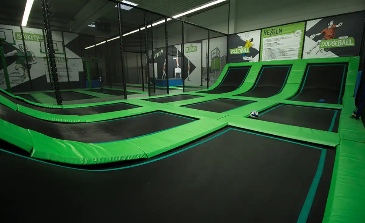 Ein Trampolinpark mit grünen und schwarzen Trampolinen, ideal für Spaß und Bewegung in einer lebhaften Umgebung.