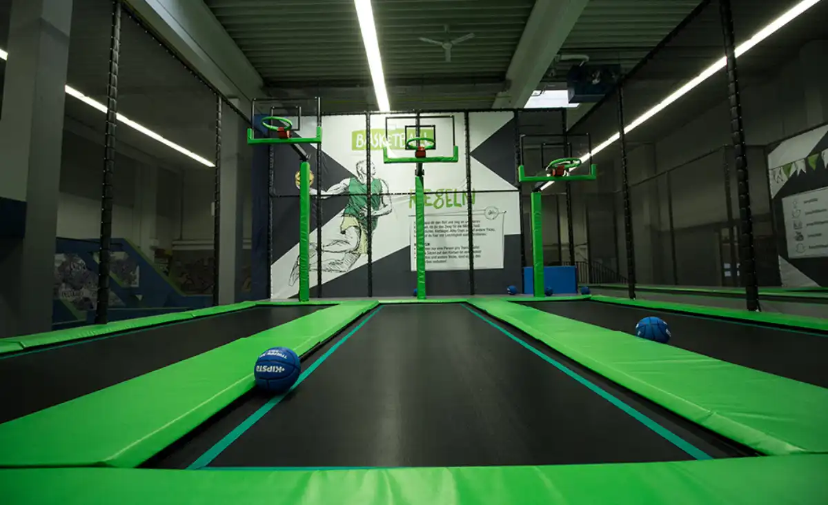 Trampolinpark mit Basketballkörben und Bällen, ideal für sportliche Aktivitäten und Spaß für alle Altersgruppen.