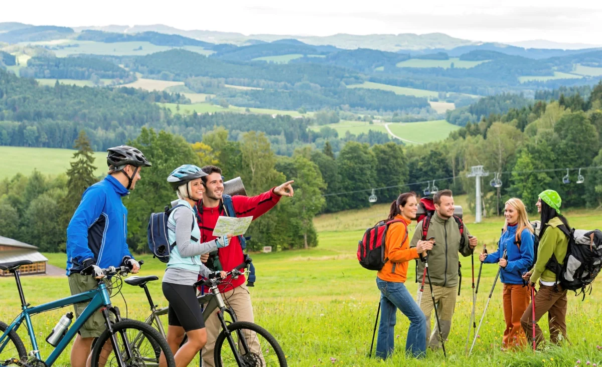 Eine Gruppe von Menschen mit Fahrrädern auf einem Berggipfel, umgeben von atemberaubender Natur.