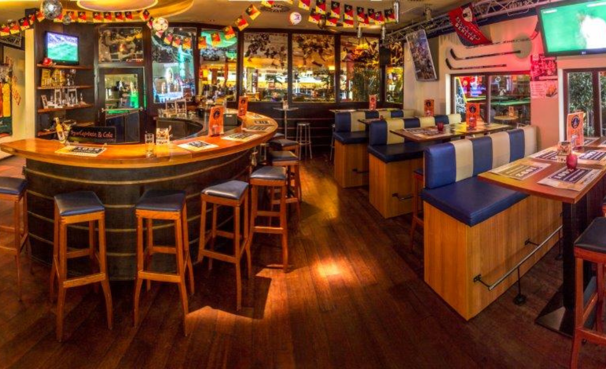 Eine Bar mit einem großen Fernseher und einer einladenden Theke, ideal für gesellige Abende und Sportübertragungen.