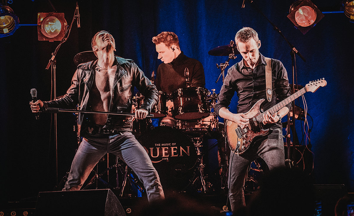 Die Band Queens spielt live auf der Bühne mit energiegeladenen Performances und beeindruckender Lichtshow.