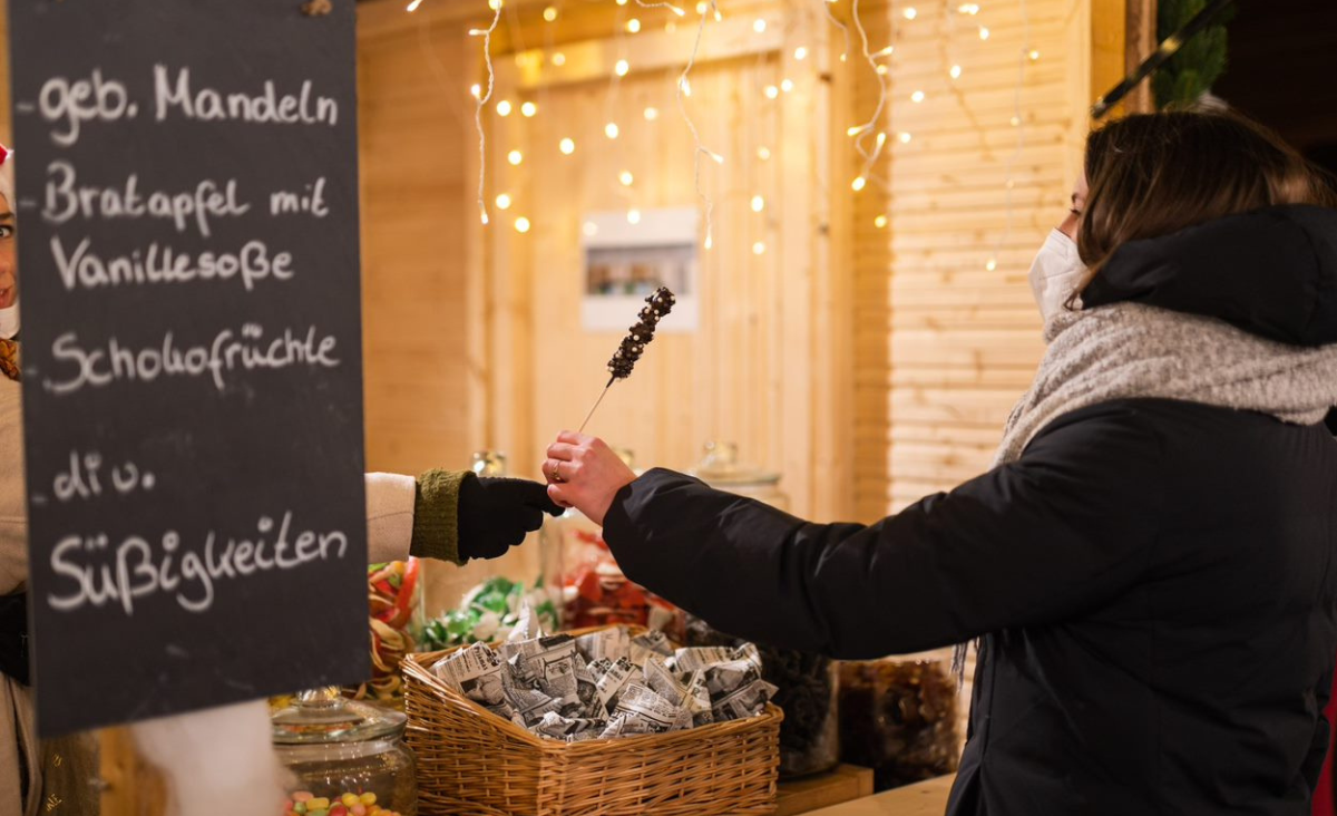 Eine Frau kauft Süßigkeiten an einem Stand auf einem Weihnachtsmarkt.