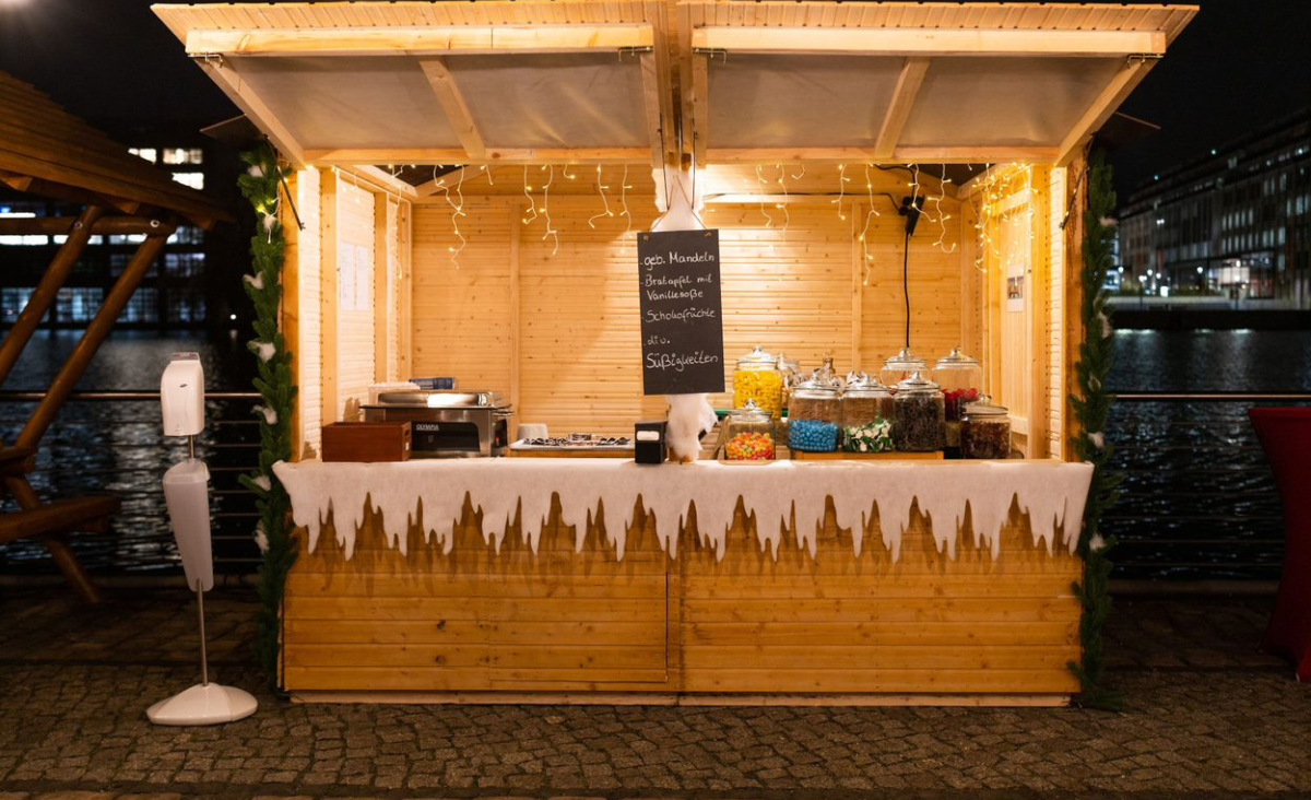 Ein kleiner Imbissstand mit einem geschmückten Weihnachtsbaum darauf, der festliche Stimmung verbreitet.