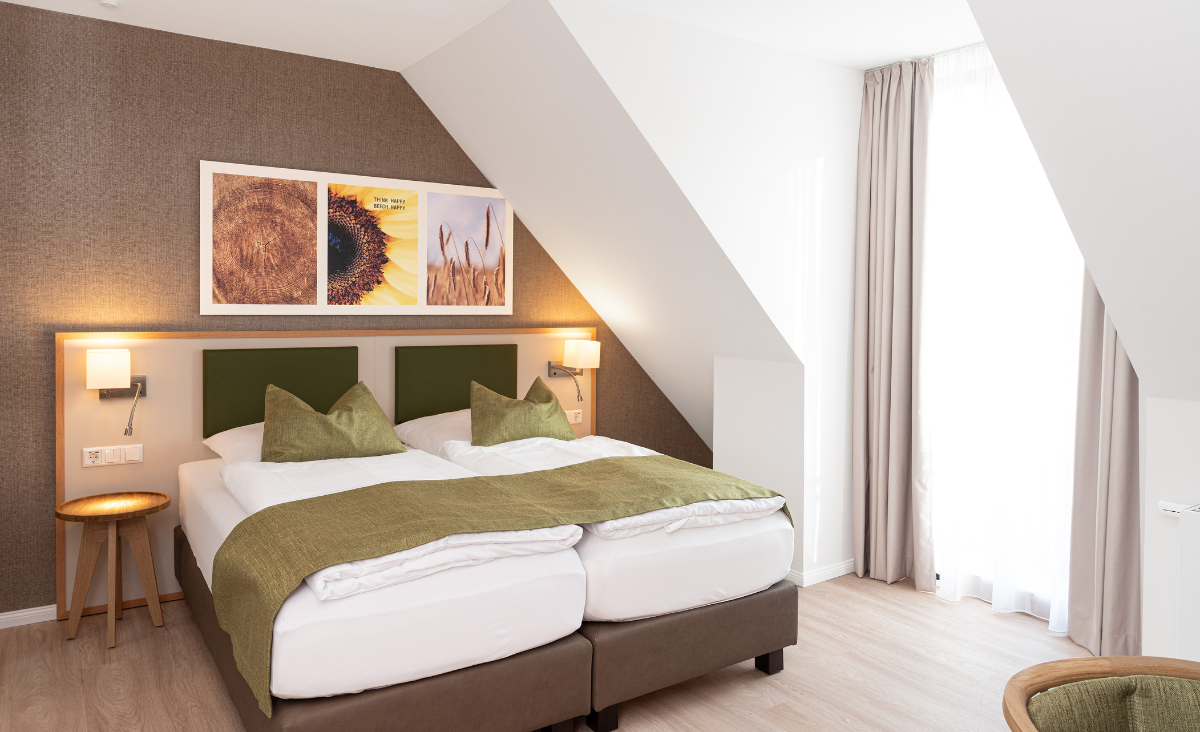 Ein gemütliches Bett in einem Raum mit einem Fenster und einem schönen Gemälde an der Wand.