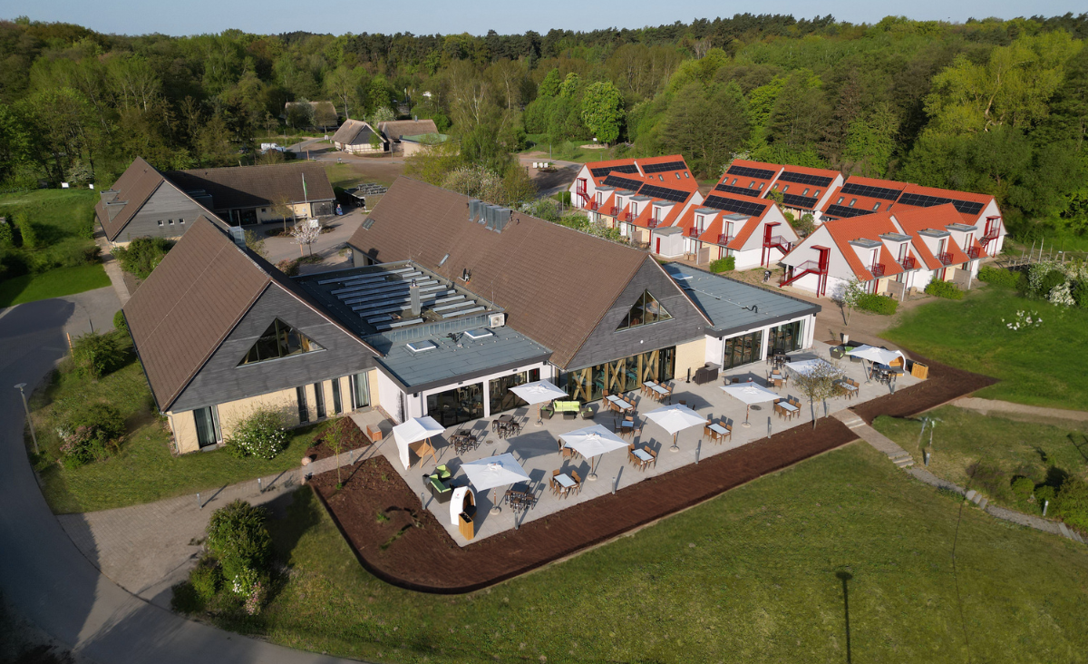 Luftaufnahme eines Resorts mit einem einladenden Swimmingpool in der Mitte, umgeben von grünen Gärten und Sonnenliegen.