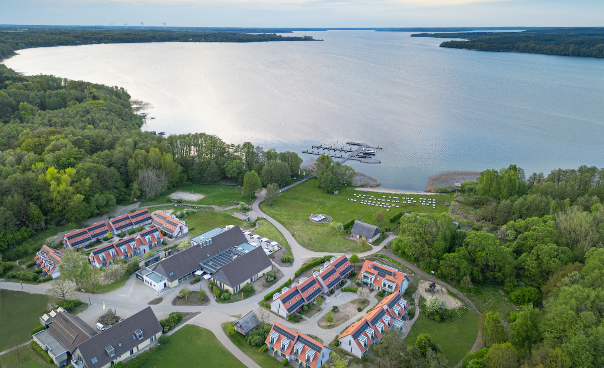 Luftaufnahme eines Resorts am Ufer eines Sees, umgeben von üppiger Natur und klaren Wasserflächen.