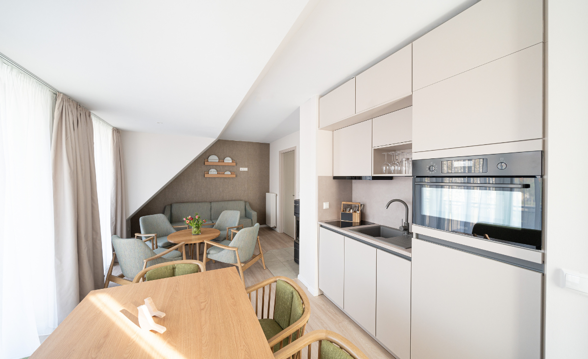 Moderne Küche und Essbereich in einer kleinen Wohnung, elegant und funktional gestaltet, mit hellen Farben und zeitgemäßen Möbeln.