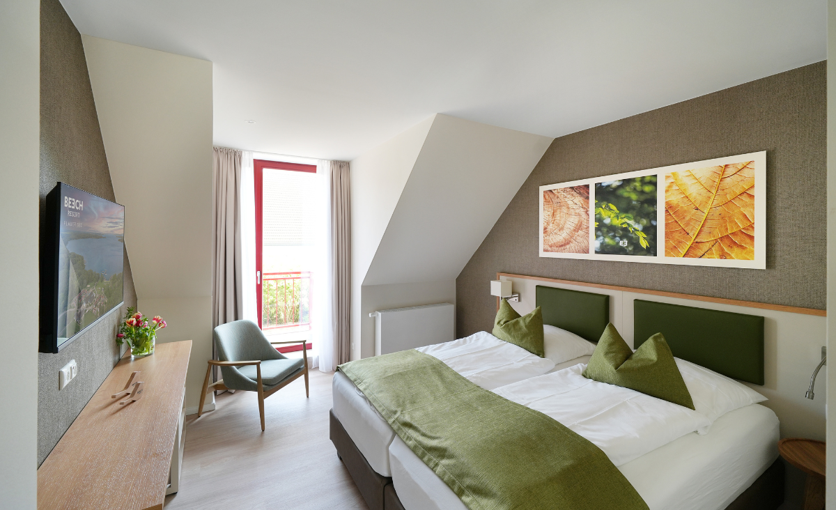 Hotelzimmer mit zwei Betten und Fernseher, ideal für einen komfortablen Aufenthalt.