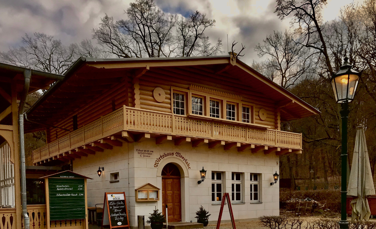Kleines Holzhaus mit Balkon und Schild, Eingang zum historischen Wirtshaus Moorlake.