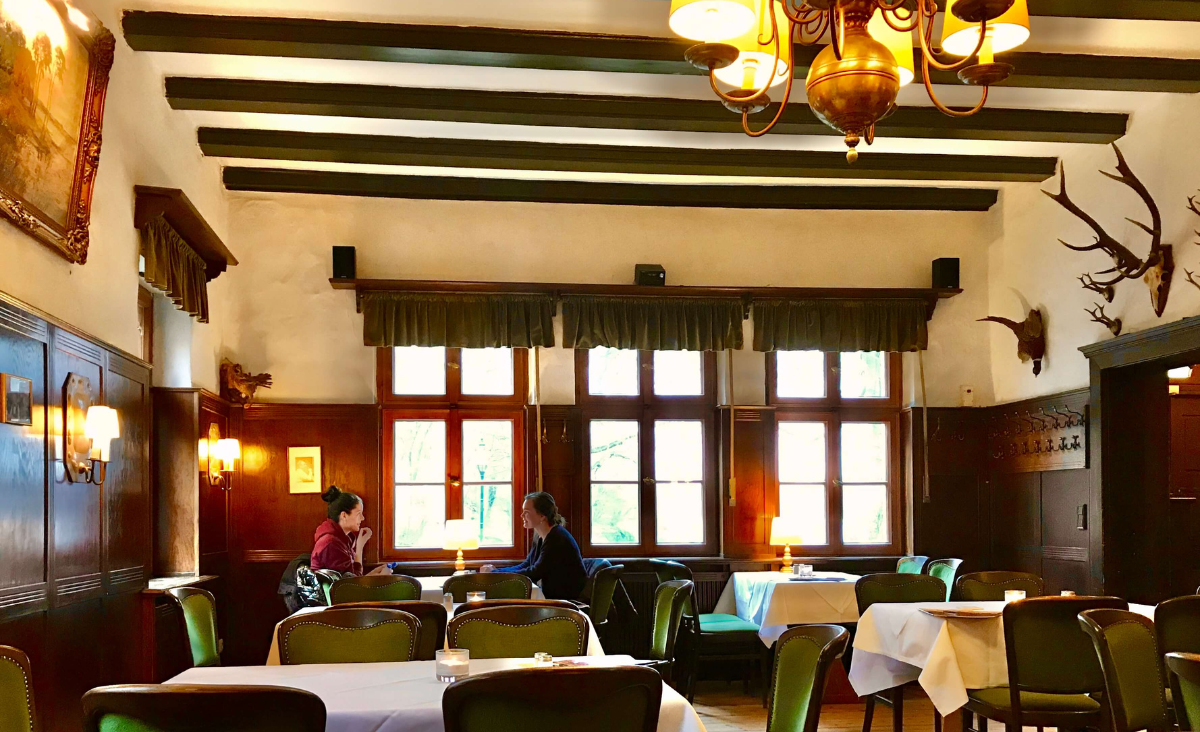 Ein stilvolles Restaurant mit Tischen und Stühlen, das eine warme Atmosphäre für ein entspanntes Essen bietet.