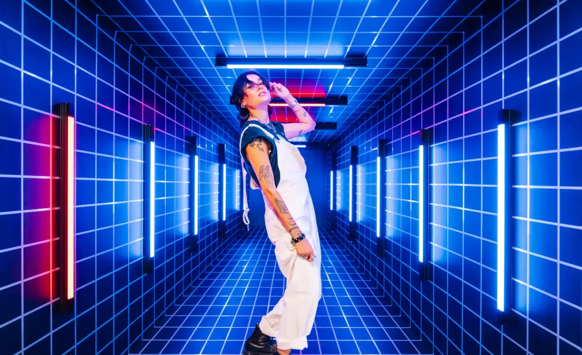 Ein Mann steht in einem Neon-Tunnel, umgeben von leuchtenden Neonlichtern in verschiedenen Farben.