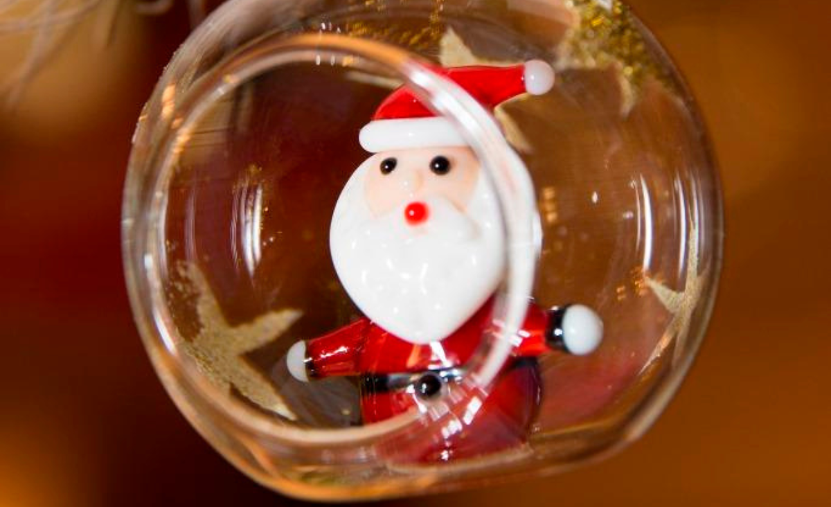 Ein gläserner Christbaumschmuck mit einer Santa Claus-Figur im Inneren.