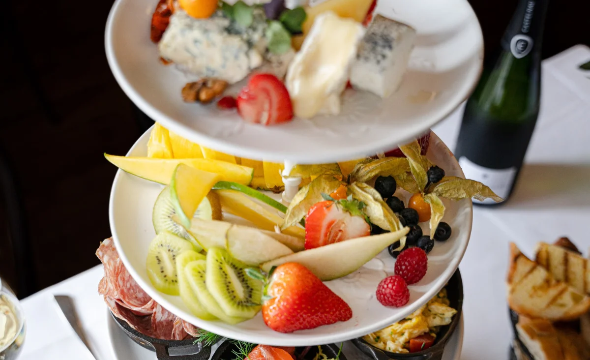 Stapel von Tellern, gekrönt mit einer Auswahl an frischem Obst und Käse, präsentiert für eine festliche Gelegenheit.