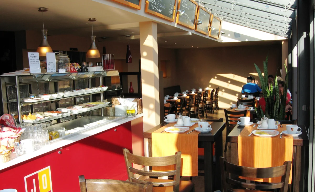 Ein Restaurant mit einem großen Fenster, das viel Tageslicht hereinlässt und eine einladende Atmosphäre schafft.
