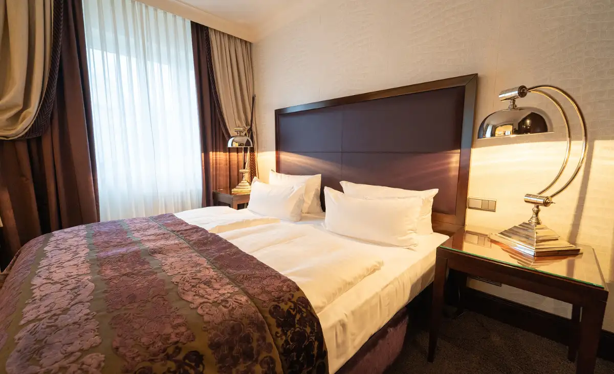 Ein gemütliches Hotelzimmer mit einem Bett und zwei stilvollen Lampen, die eine einladende Atmosphäre schaffen.