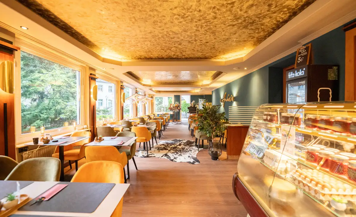 Ein Restaurant mit einem großen Fenster, das viel Tageslicht hereinlässt und eine einladende Atmosphäre schafft.