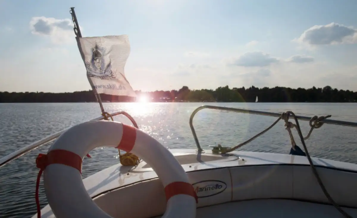 Ein Sportboot mit einer Fahne am Bug, das sanft auf dem Wasser schaukelt.