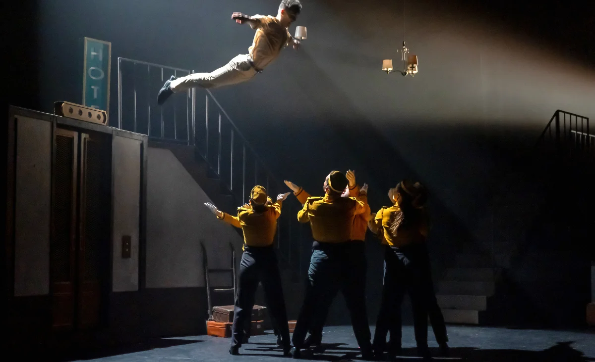 Ein Mann schwebt in der Luft, umgeben von einer Gruppe von Menschen, die begeistert zuschauen. Gutschein für Stories The Tap Dance Sensation.