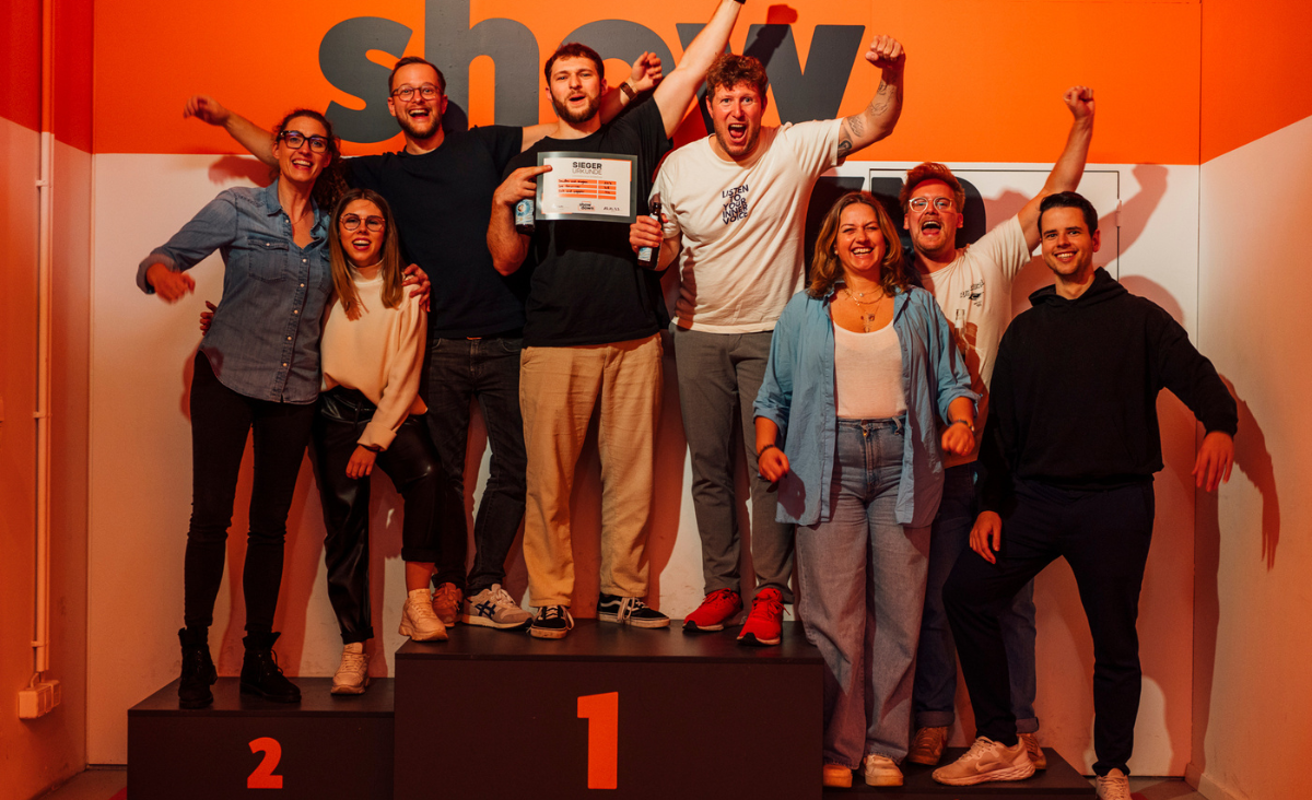 Die Gewinner des Wettbewerbs "Your Showdown" stehen stolz auf der Bühne und halten ihre Trophäen in den Händen.