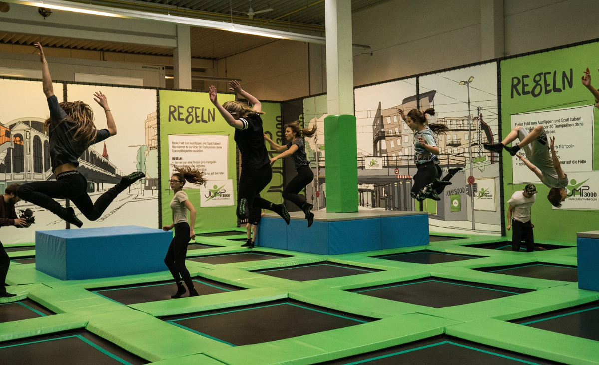 Menschen springen fröhlich auf Trampolinen in der Jum3000 Trampolinhalle in Berlin.