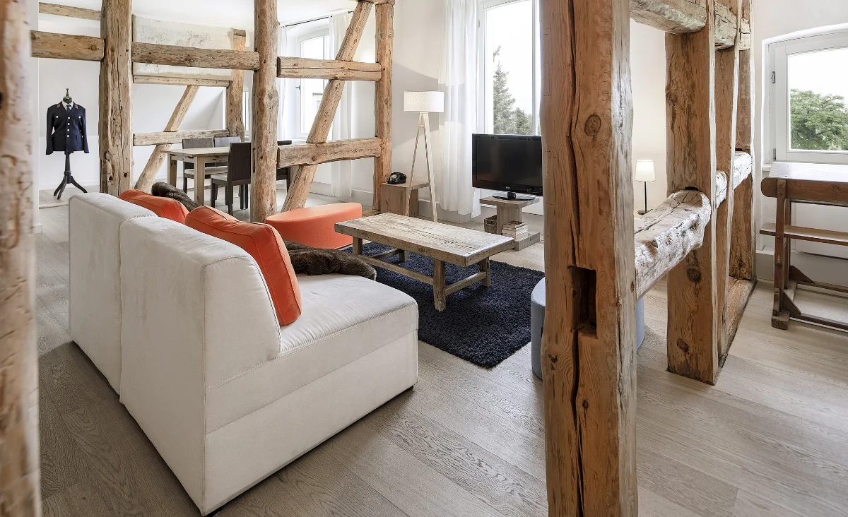 Ein Wohnzimmer mit Holzdeckenbalken und einer gemütlichen Couch, die eine einladende Atmosphäre schafft.