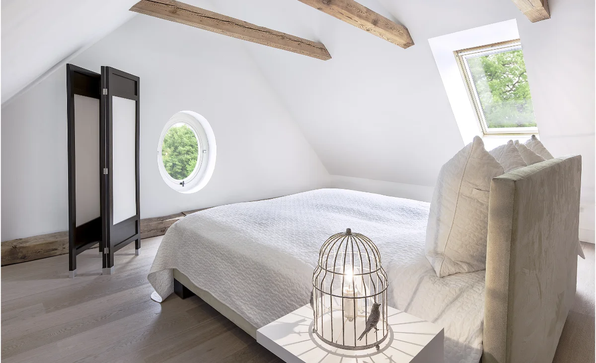 Ein Schlafzimmer mit einem Bett und einem Vogelkäfig, der eine gemütliche und einladende Atmosphäre schafft.
