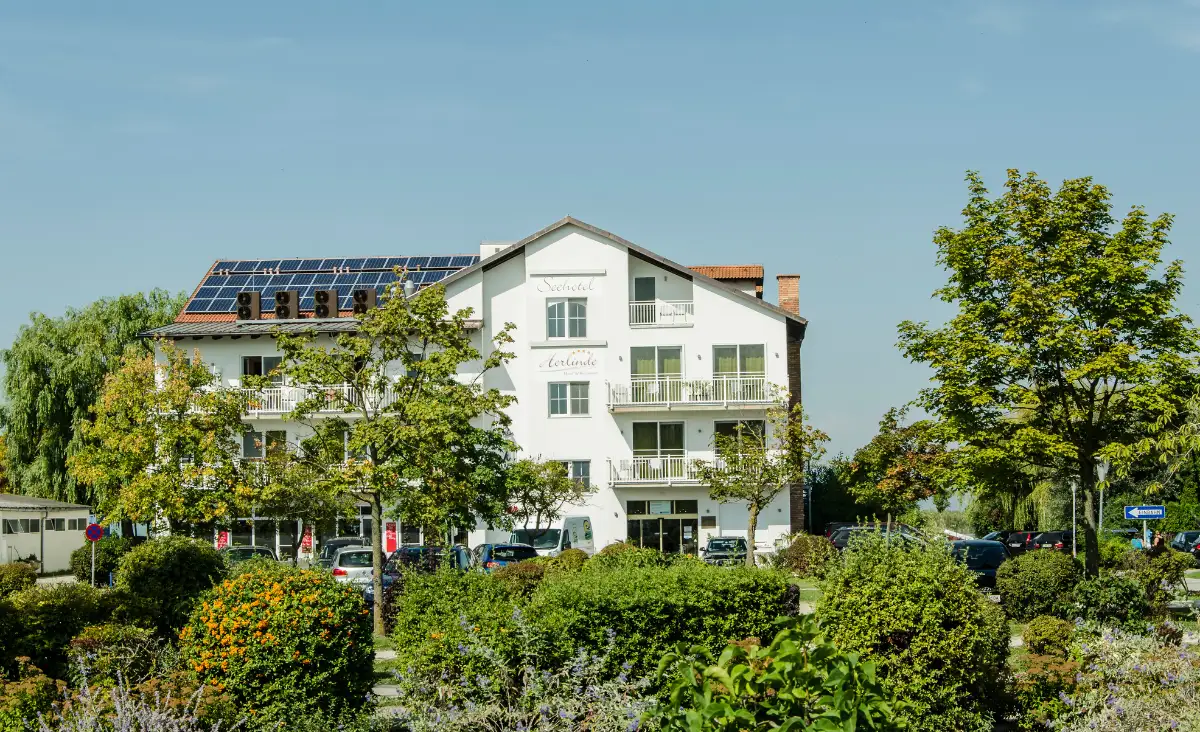 Das Seehotel Herlinde: Ein imposantes weißes Gebäude mit Solarpanelen, harmonisch in die Natur integriert.