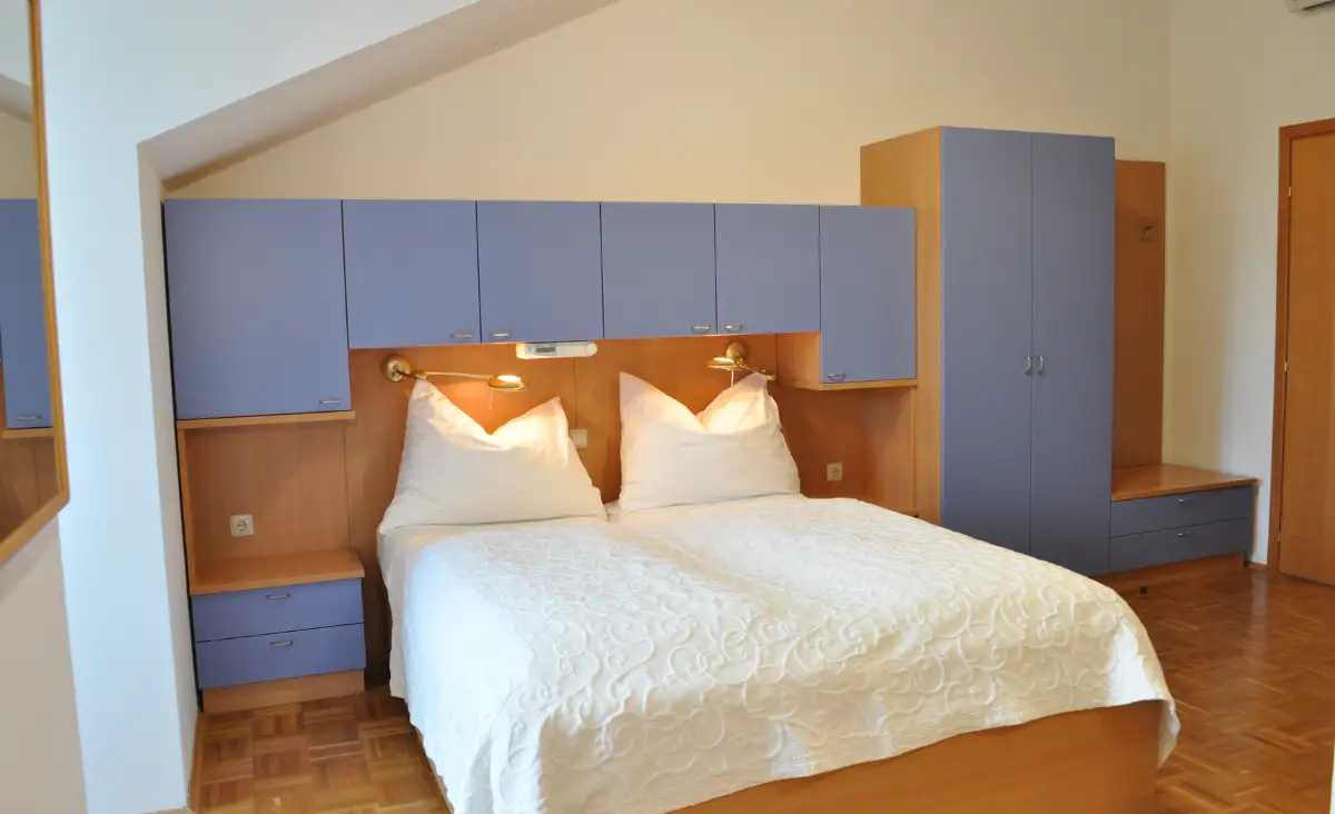 Ein elegantes Bett mit weißen Bettlaken im Seehotel Herlinde, das Ruhe und Luxus ausstrahlt.
