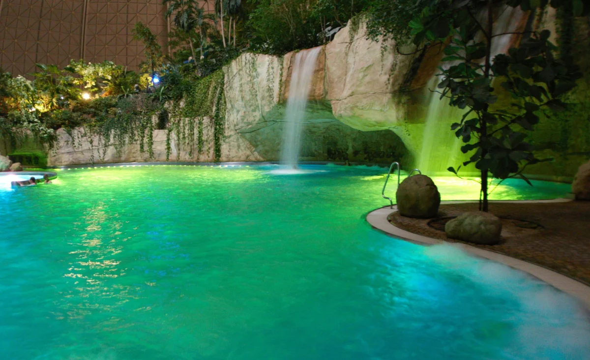Ein Pool mit klarem Wasser und einem sanft plätschernden Wasserfall im Hintergrund.
