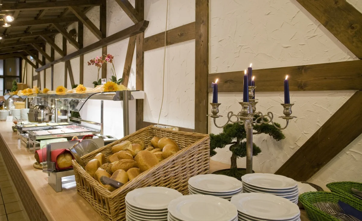 Ein Buffet mit frischem Brot, eleganten Tellern und stimmungsvollen Kerzen dekoriert.