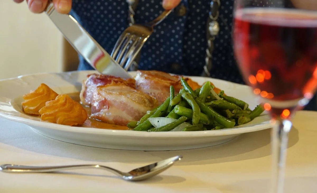 Ein Teller mit Essen, begleitet von einer Gabel und einem Messer, präsentiert eine appetitliche Mahlzeit.