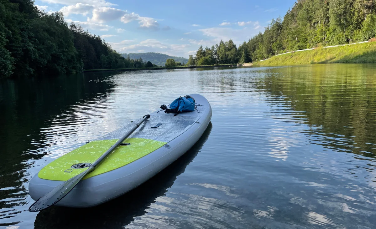 Ein Kajak schwebt ruhig auf einem See, während ein Paddel daneben liegt.