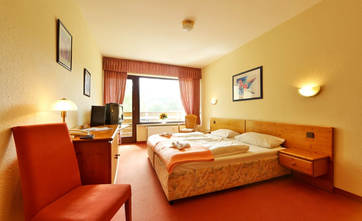 Ein Bett in einem Raum, umgeben von Wänden und einem Fenster, das Tageslicht hereinlässt.