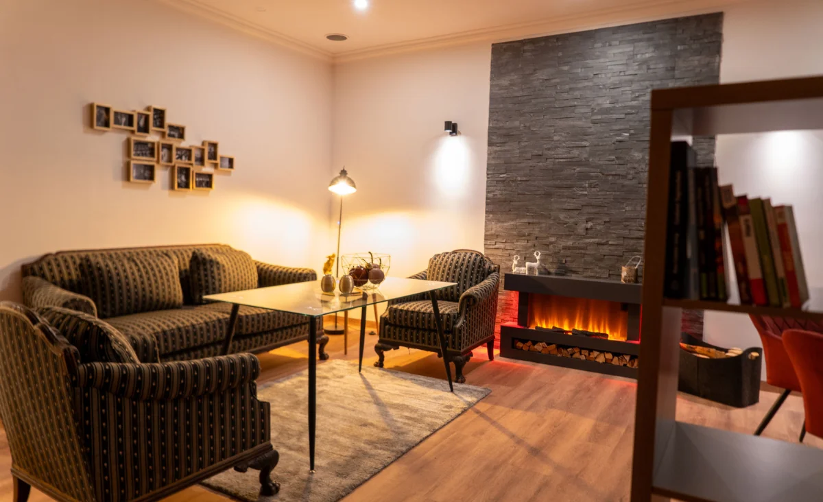 Ein Wohnzimmer mit einem Kamin und bequemen Sofas, das eine gemütliche Atmosphäre ausstrahlt.