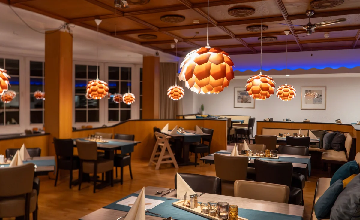 Ein Restaurant mit Tischen und Stühlen in der Mitte des Raumes, das eine einladende Atmosphäre schafft.