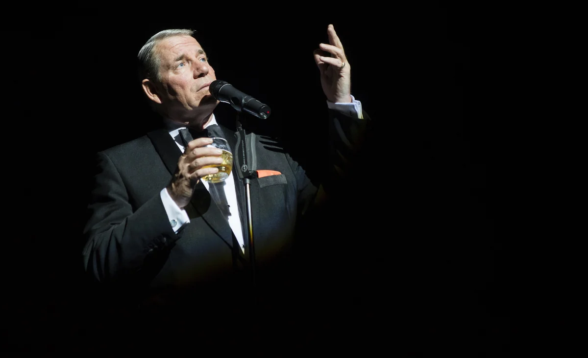 Ein Mann im Smoking hält ein Mikrofon und singt bei der Show "Sinatra & Friends"