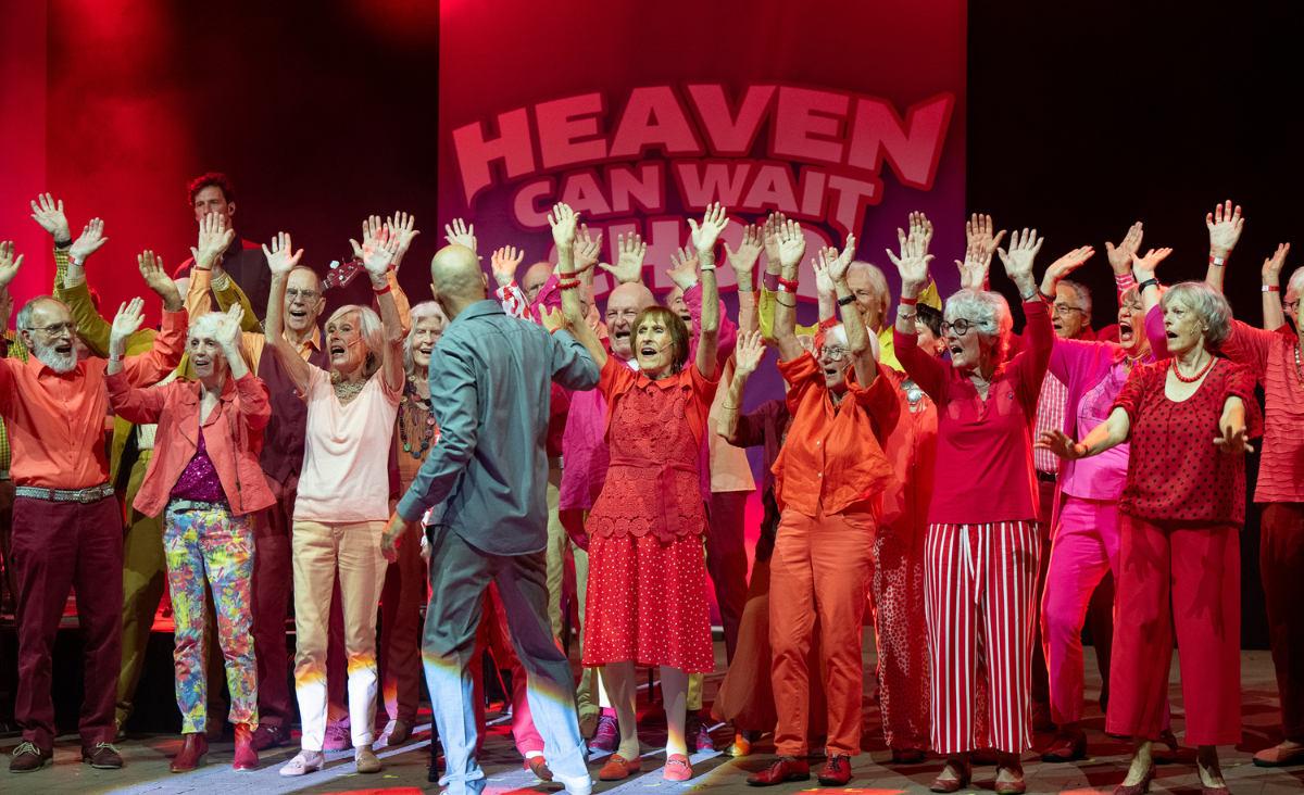 Fröhliche Senioren in bunten Kleidern, die als Chor "Heaven can wait" aufführen und eine lebendige Stimmung verbreiten.