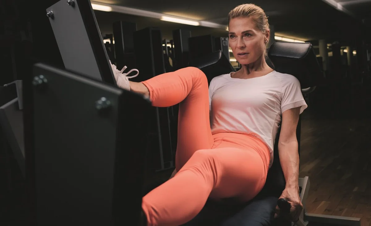 Frau im pfirsichfarbenen T-Shirt trainiert an Kraftgerät im Kieser Trainingsstudio