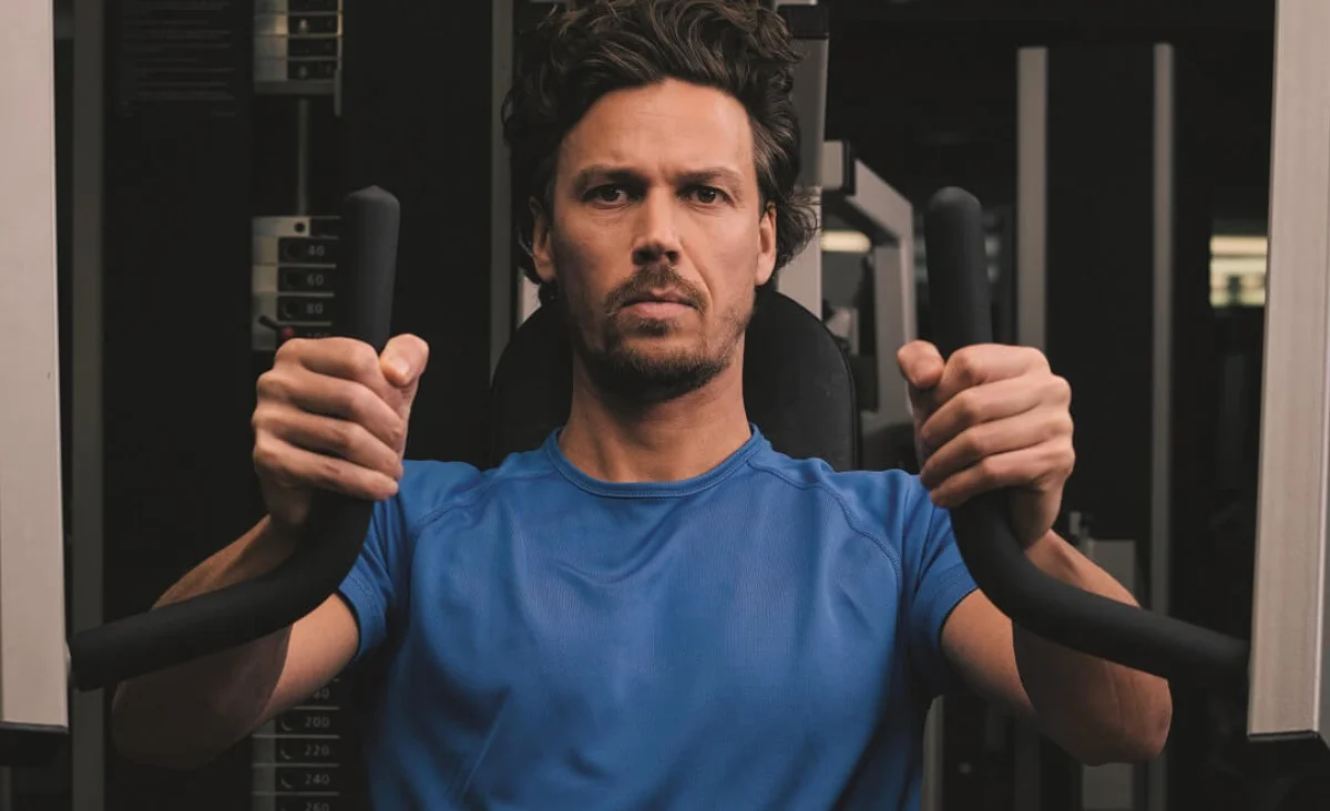 Mann in blauem T-Shirt trainiert an Kraftgerät im Kieser Trainingsstudio