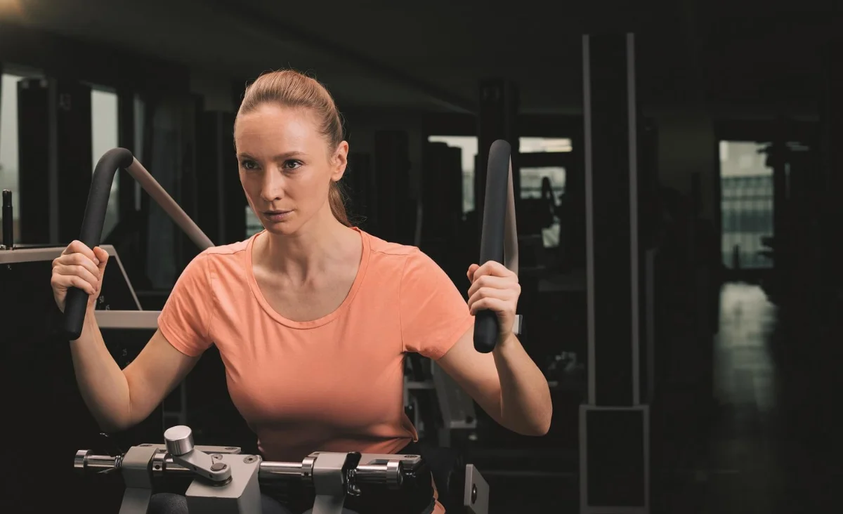 Frau im pfirsichfarbenen T-Shirt trainiert an Kraftgerät im Kieser Trainingsstudio