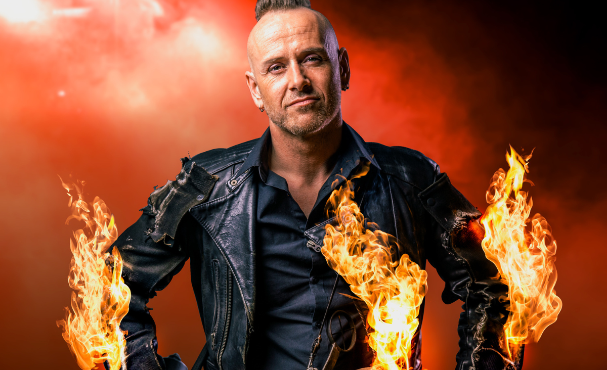 Ein Mann, der einen Feuerstock und ein Messer hält, in der gruseligen Kulisse des Zirkus des Horrors in Berlin.