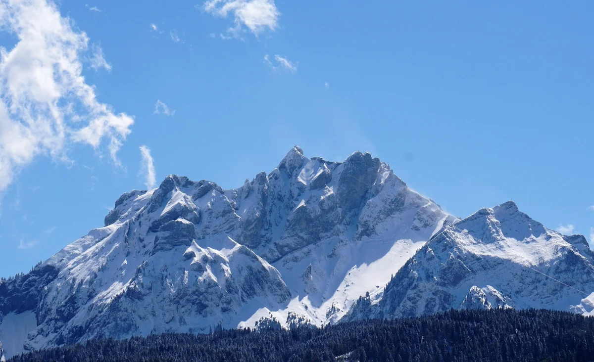 Winterlandschaft mit schneebedecktem Berg und klarem blauen Himmel.