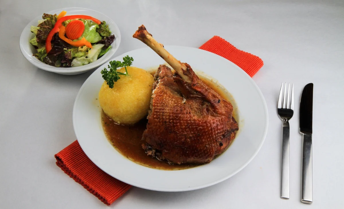 Ein Teller, der eine goldbraune Gans und Klößen zeigt, klassisch für Weihnachten.