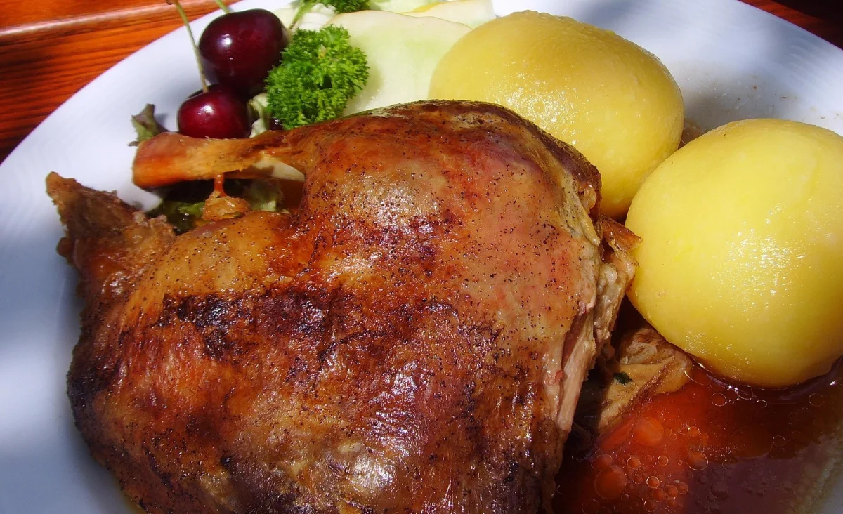 Ein Teller, der eine goldbraune Gans und Klößen zeigt, klassisch für Weihnachten.