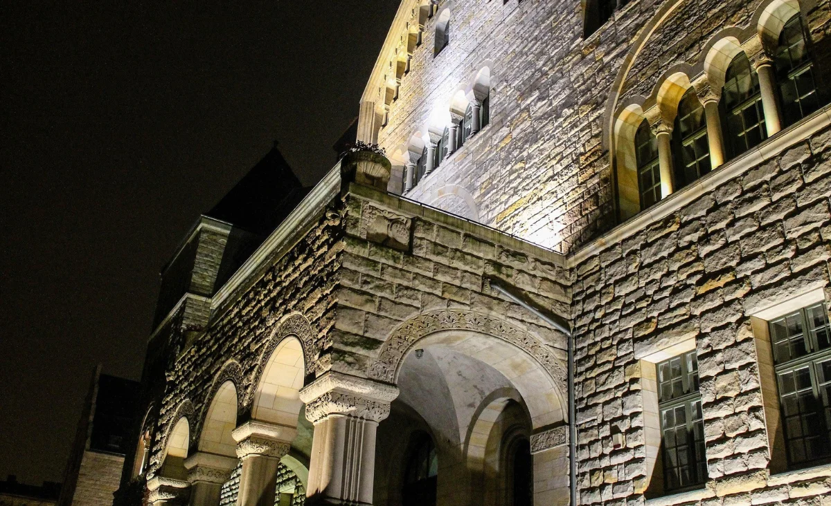 Ein Gebäude mit einem Uhrturm, das nachts erleuchtet ist.