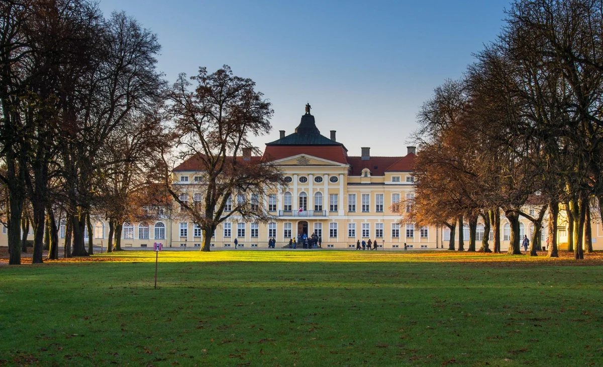 Ein Gebäude, umgeben von Bäumen und Gras, in einer grünen Umgebung.